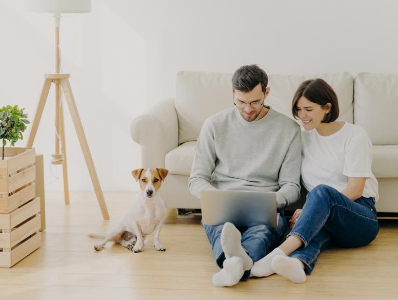Couple with dog looks at laptop
