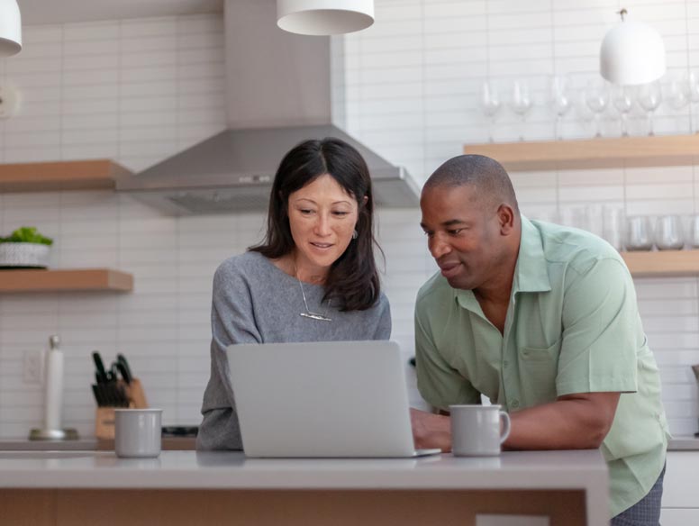 Couple looks at laptop in kitchen